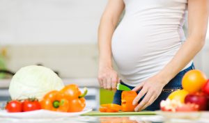 Femme enceinte coupant des légumes